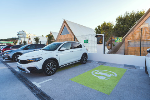 Coche eléctrico estacionado en punto de carga en Camping Costa del Sol Glamping Village, Andalucía, España.