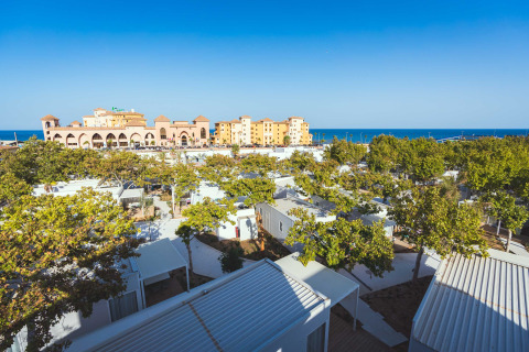 Camping Costa del Sol Glamping Village in Andalusia, Spain, featuring cabins, trees, and a view of the sea.