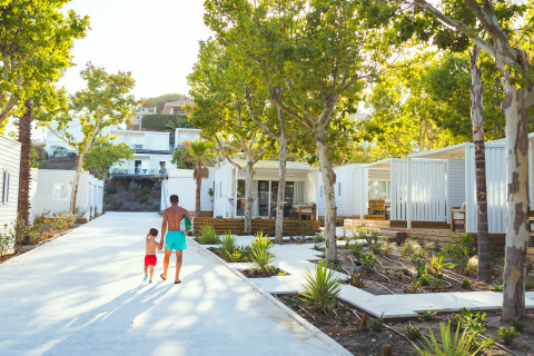 Father and son walking among modern cabins surrounded by trees at Costa del Sol Glamping Village, Andalusia.