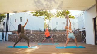 Tres personas practicando yoga sobre esterillas bajo una cubierta en Camping Costa del Sol Glamping Village, Andalucía.