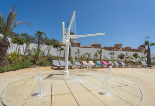 Waterspeelplek met fonteintjes en ligstoelen onder blauwe lucht aan Camping Costa del Sol Glamping Village, Spanje.