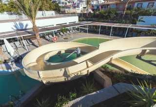 Waterglijbaan over het zwembad bij Camping Costa del Sol Glamping Village in Andalusië, Spanje, met terrasstoelen.