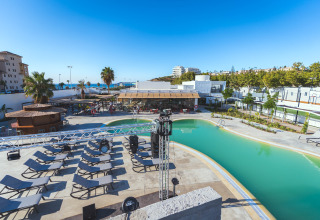 Buitenzwembad, ligzetels en bar aan Camping Costa del Sol Glamping Village in Andalusië, Spanje.