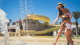 Madre e hija juegan junto a chorros de agua en Camping Costa del Sol Glamping Village en Andalucía, España.