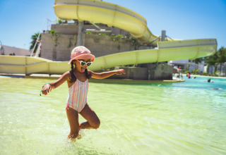Meisje speelt in het zwembad bij een gele glijbaan op Camping Costa del Sol Glamping Village in Andalusië.