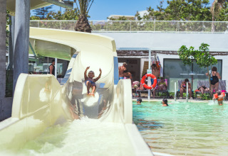 Een kind glijdt van een waterglijbaan het zwembad in bij Camping Costa del Sol Glamping Village in Andalusië.