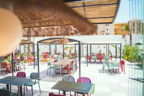 Espace de restauration extérieur avec chaises et tables colorées au Camping Costa del Sol Glamping Village, Andalousie, Espagne.