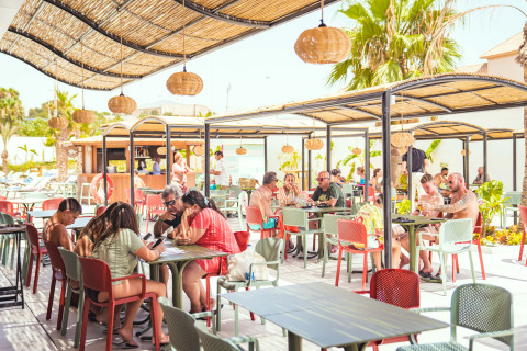 Zona pranzo all'aperto al Camping Costa del Sol Glamping Village in Andalusia, Spagna, con ospiti al sole.