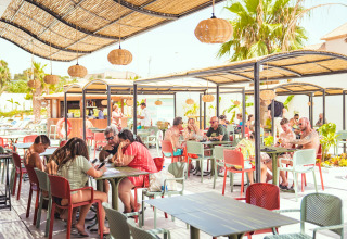 Outdoor dining area at Camping Costa del Sol Glamping Village in Andalusia, Spain, with guests enjoying sunny weather.