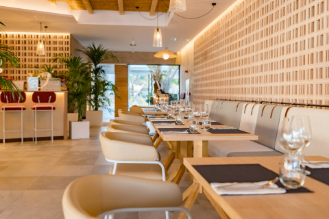 Interior moderno de restaurante en Camping Costa del Sol Glamping Village con mesas elegantes y plantas verdes.