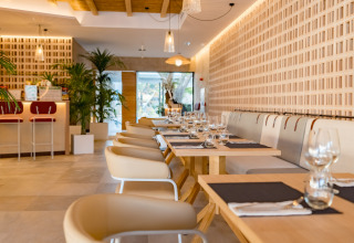 Modern restaurant interior at Camping Costa del Sol Glamping Village with stylish tables, chairs, and plants.