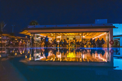 Night view of a poolside restaurant at Camping Costa del Sol Glamping Village, Andalusia, Spain, with reflections.