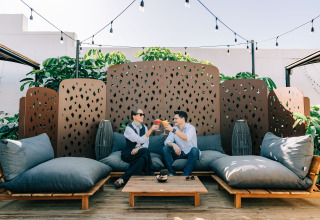 Two people enjoy drinks together at Camping Costa del Sol Glamping Village in Andalusia, Spain, on a patio.