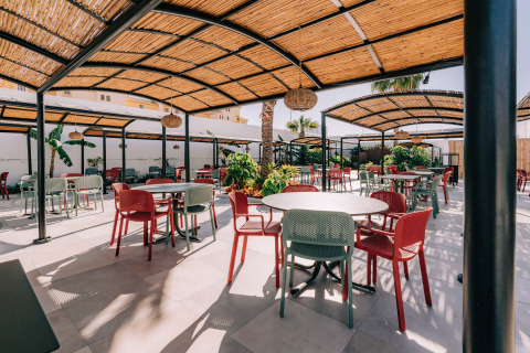 Zona de comedor exterior en Camping Costa del Sol Glamping Village con sillas coloridas y pérgolas de sombra.