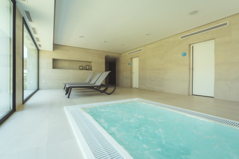 Zona de spa interior con jacuzzi y tumbonas en Camping Costa del Sol Glamping Village en Andalucía, España.