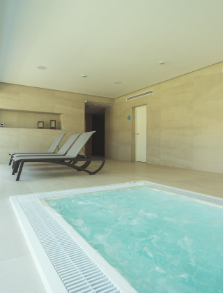 Zona de spa interior con jacuzzi y tumbonas en Camping Costa del Sol Glamping Village en Andalucía, España.