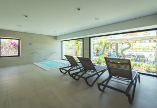 Zona de relax interior con tumbonas y jacuzzi en Camping Costa del Sol Glamping Village, Andalucía, España.