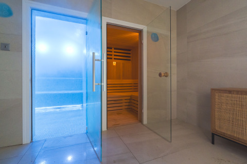 Indoor spa area with glass doors leading to a sauna and steam room at Camping Costa del Sol Glamping Village.