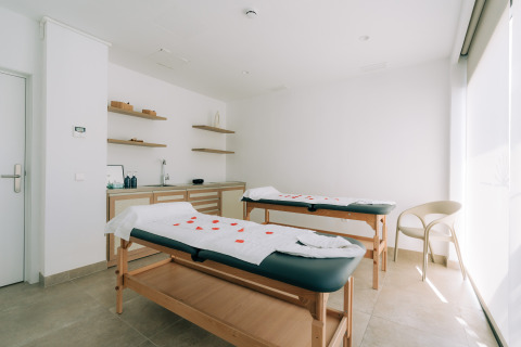 Bright and modern spa room with two massage beds, light decor and shelves at Camping Costa del Sol Glamping Village.
