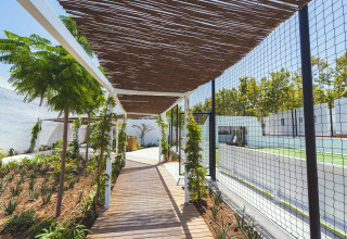 Houten wandelpad met pergola aan sportveld in Camping Costa del Sol Glamping Village, Andalusië, Spanje.