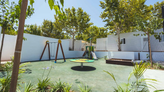 Parque infantil con columpios, tobogán y carrusel en Camping Costa del Sol Glamping Village, Andalucía.