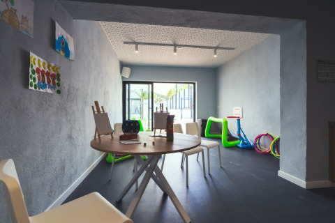 Sala de juegos infantil con mesas, caballetes y juguetes en Camping Costa del Sol Glamping Village, Andalucía.
