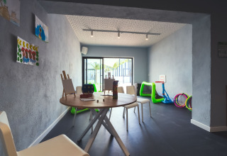 Kinderruimte met tafels, schildersezels en speelgoed in Camping Costa del Sol Glamping Village, Andalusië.