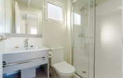 Salle de bain moderne et lumineuse dans un lodge avec douche, toilettes, lavabo et grand miroir.