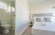 Habitación luminosa en una cabaña con cama doble, dos almohadas, toallas limpias y baño privado con ducha.