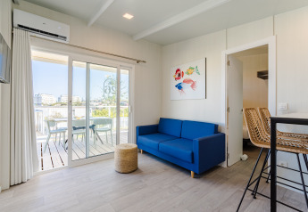 Lyst opholdsrum i Bungalow Leo med blå sofa, havudsigt og moderne indretning på Camping Costa del Sol.