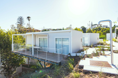 Bungalow Leo Sea View, ein moderner Bungalow mit Terrasse, Balkon und Blick ins Grüne, bei Sonnenschein.