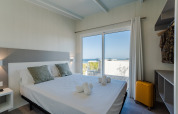 Schlafzimmer im Bungalow Leo Sea View mit Doppelbett, moderner Einrichtung und Meerblick in Spanien.