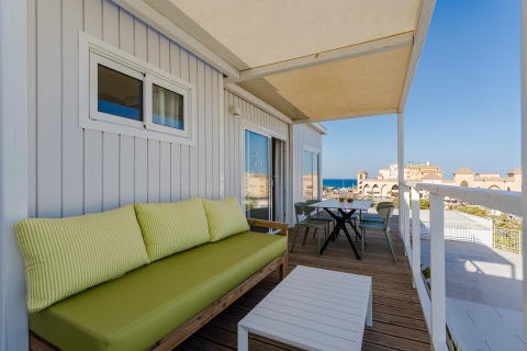 Terraza con sofá verde, mesa y vistas al mar en Bungalow Leo Sea View, Camping Costa del Sol Glamping Village.