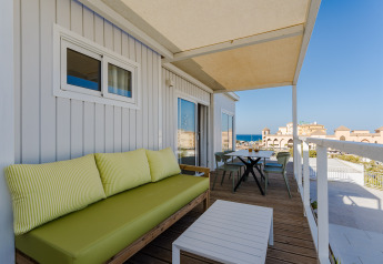 Terraza con sofá verde, mesa y vistas al mar en Bungalow Leo Sea View, Camping Costa del Sol Glamping Village.