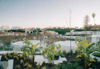 Vue sur des bungalows modernes et des palmiers au Camping Costa del Sol Glamping Village, Espagne, au coucher du soleil.