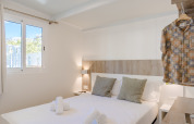 Camera di lodge moderna con letto matrimoniale, dettagli in legno, vista finestra e camicia appesa.