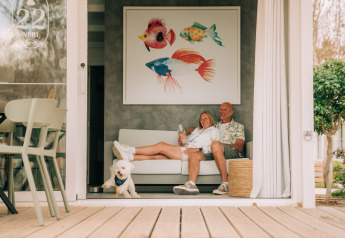 Ein Paar entspannt sich mit Hund und Wein auf dem Sofa in Bungalow Neri Pet Friendly, Costa del Sol Glamping Village.