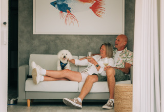 Pareja relajándose con su perro y vino en Bungalow Neri de Camping Costa del Sol Glamping Village, España.