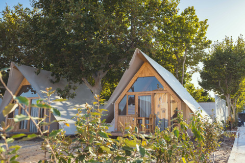 Moderne A-vormige lodges onder bomen bij Camping Costa del Sol Glamping Village, Spanje, op een zonnige dag.