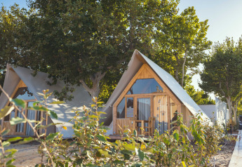 Lodge moderni a forma di A sotto gli alberi al Camping Costa del Sol Glamping Village, Spagna, in una giornata soleggiata.