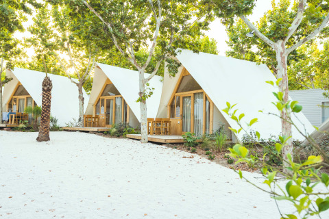 Weiße, dreieckige Glamping-Lodges mit Holzterrassen und Bäumen im Camping Costa del Sol Glamping Village, Spanien.