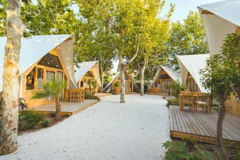 Lodges modernes en bois entourés d’arbres et chemins sablonneux à Camping Costa del Sol Glamping Village, Espagne.