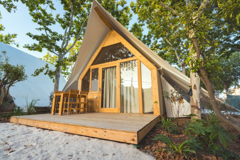 Moderne lodge genaamd Hanna met houten veranda en zitgedeelte buiten, omgeven door groene bomen.