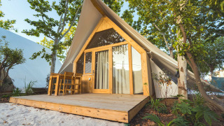 Lodge moderne nommé Hanna avec terrasse en bois et coin salon extérieur entouré d’arbres verdoyants.