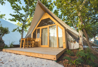 Lodge moderne nommé Hanna avec terrasse en bois et coin salon extérieur entouré d’arbres verdoyants.