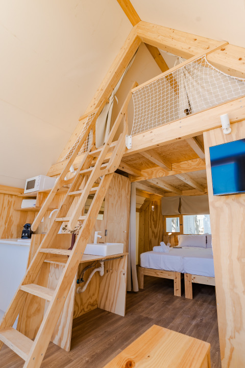 Interieur van de Hanna-lodge bij Camping Costa del Sol Glamping Village in Spanje met houten slaapzolder.