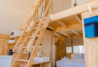 Vista interior de la lodge Hanna en Camping Costa del Sol Glamping Village en España con altillo de madera.