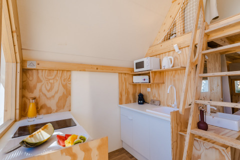 Acogedora cocina de madera con altillo, escalera y fruta fresca en Hanna, Camping Costa del Sol Glamping Village.