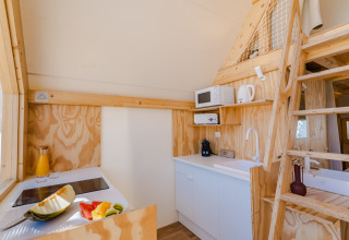 Acogedora cocina de madera con altillo, escalera y fruta fresca en Hanna, Camping Costa del Sol Glamping Village.