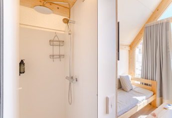 Bright shower and cozy bedroom in Hanna lodge at Camping Costa del Sol Glamping Village in Spain, sunlight fills room.
